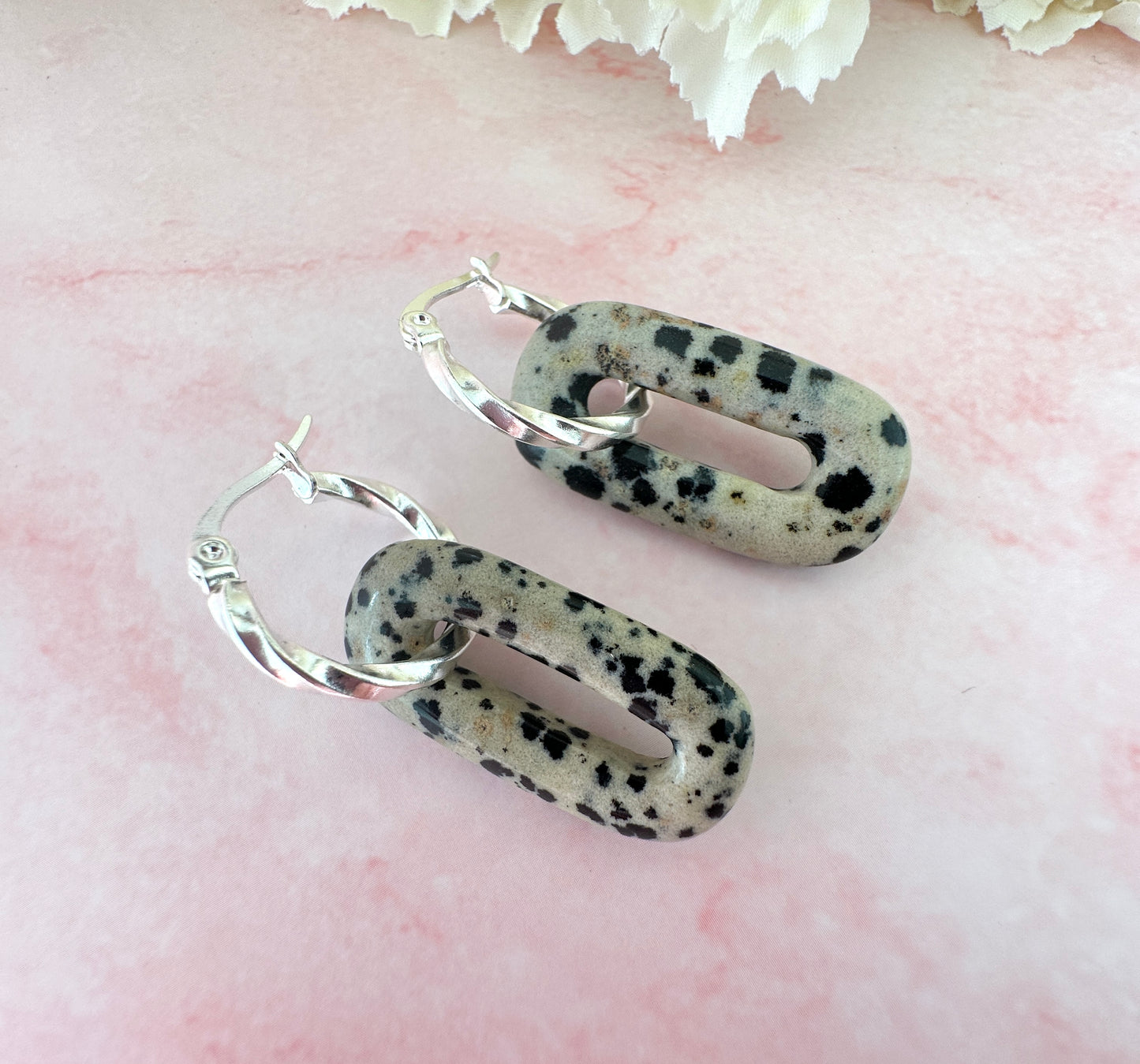 Silver Dalmatian Jasper gemstone twist hoop earrings.