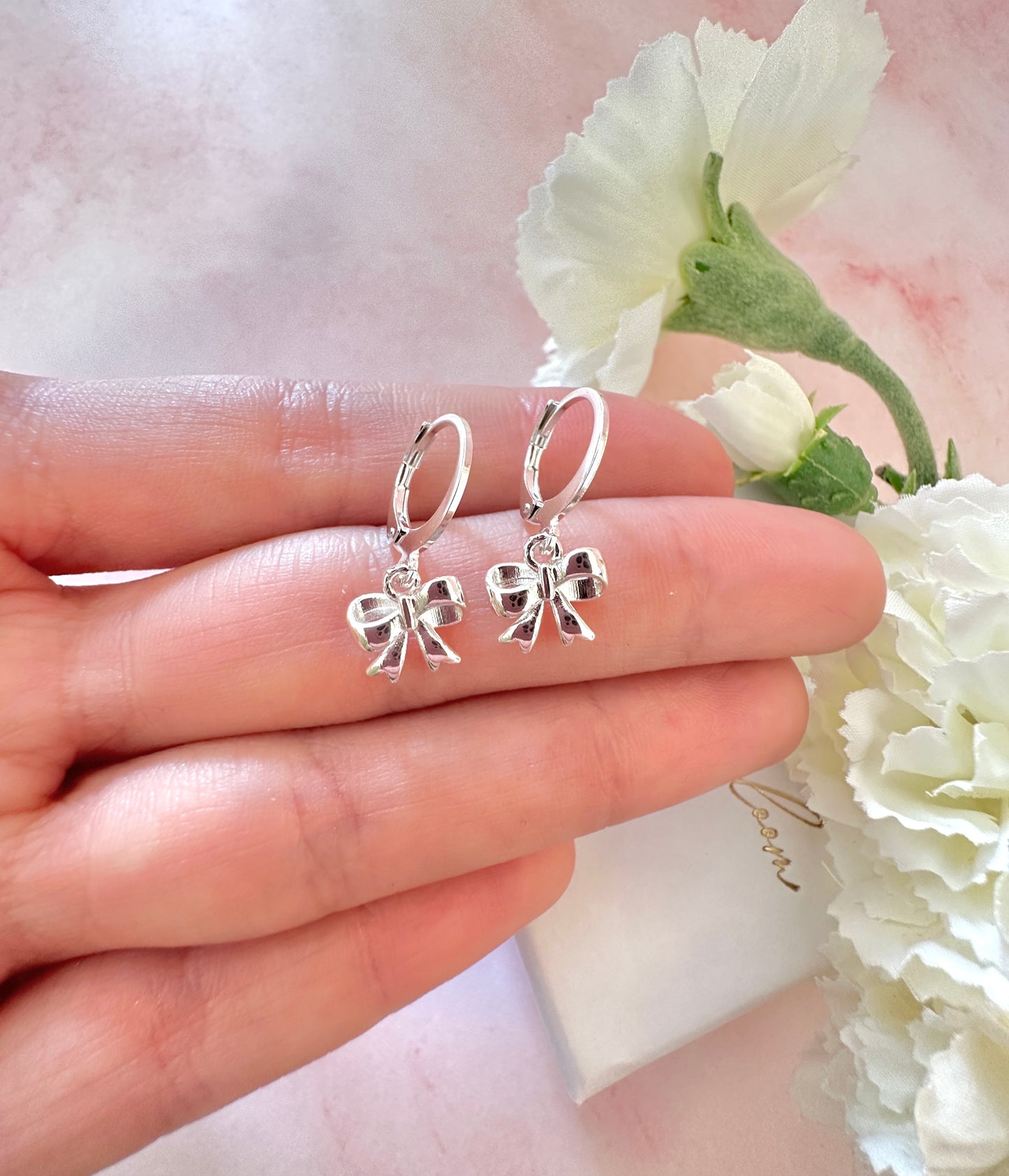 Silver Bow huggie hoop earrings.