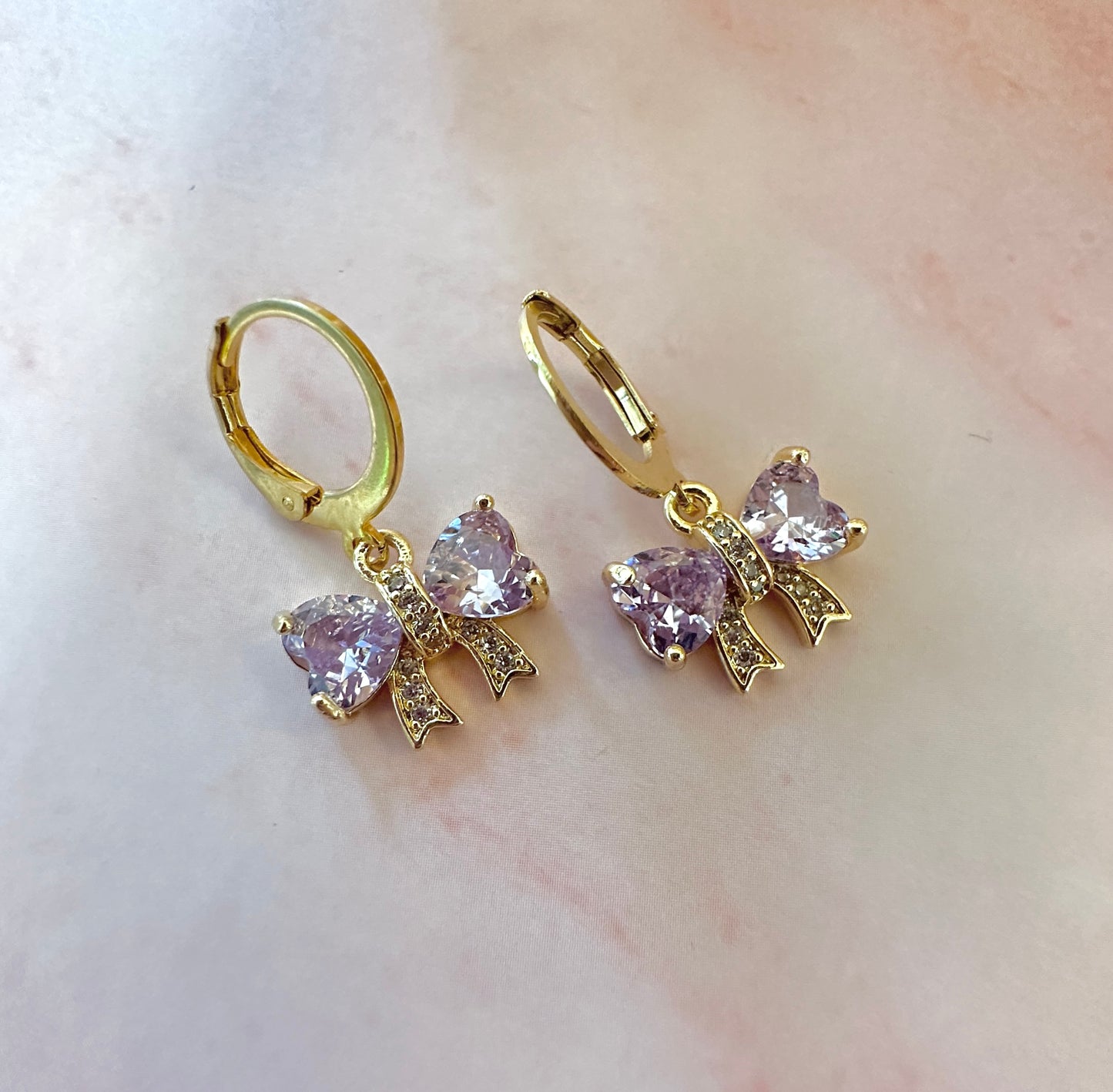 Lilac CZ Bow gold huggie hoop earrings.